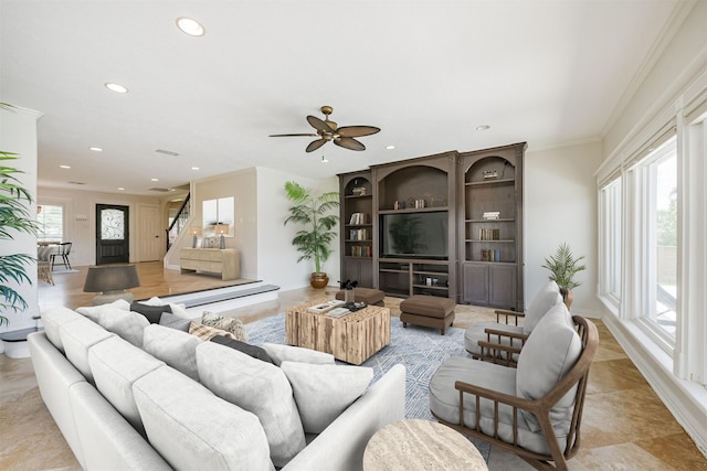 living room with a wealth of natural light, ornamental molding, and ceiling fan