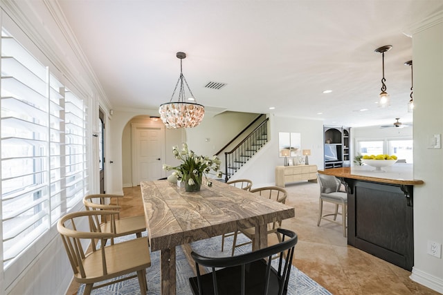 tiled dining space with ceiling fan with notable chandelier and crown molding