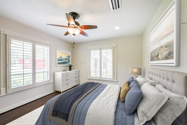 bedroom featuring ceiling fan, wood-type flooring, and a textured ceiling