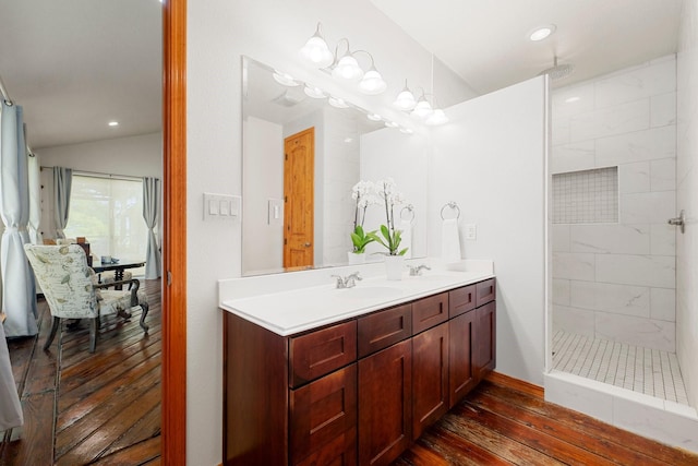 bathroom with a tile shower, vanity, hardwood / wood-style flooring, and lofted ceiling