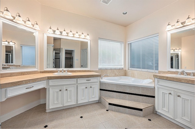 bathroom featuring tile patterned floors, a relaxing tiled tub, and vanity