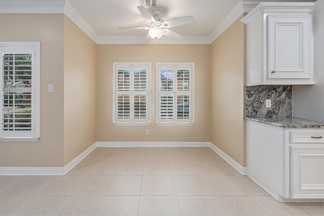 unfurnished dining area featuring ceiling fan, light tile patterned floors, and crown molding