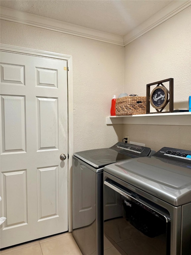 laundry room with light tile patterned floors, ornamental molding, and washing machine and clothes dryer