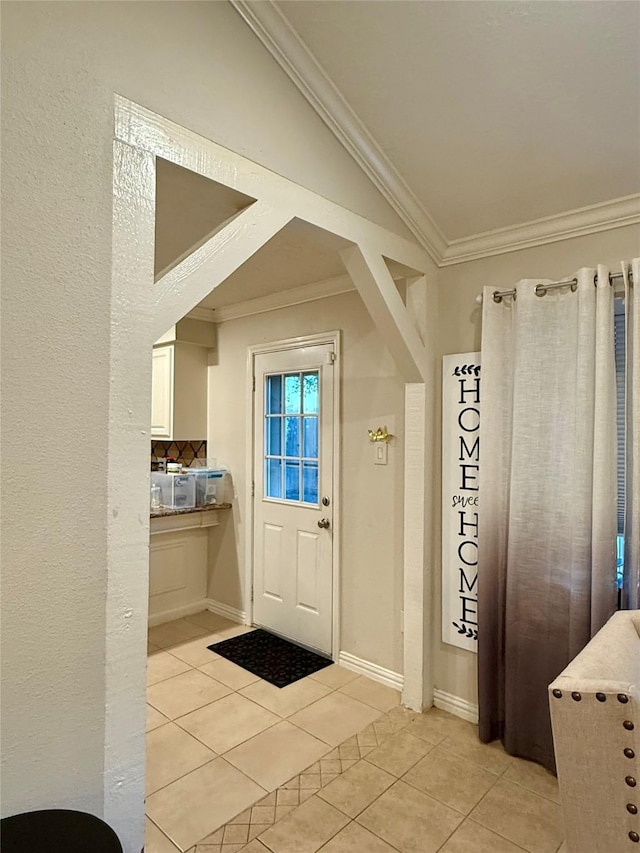 doorway to outside featuring light tile patterned floors, lofted ceiling, and ornamental molding