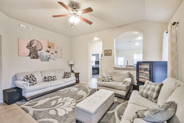 tiled living room with ceiling fan and lofted ceiling