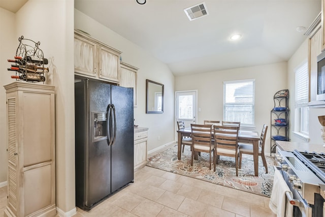 kitchen with stainless steel range, vaulted ceiling, black refrigerator with ice dispenser, and light tile patterned flooring