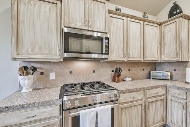 kitchen with backsplash, light brown cabinets, and stainless steel appliances