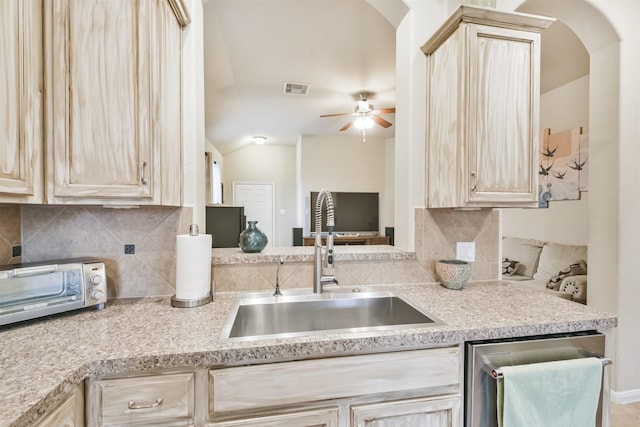 kitchen with dishwasher, light brown cabinetry, vaulted ceiling, and sink