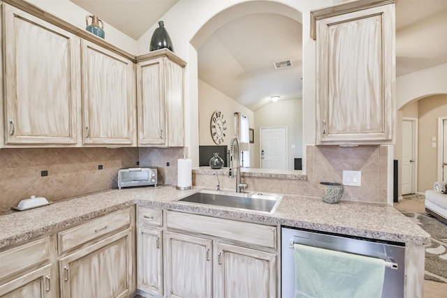 kitchen with dishwasher, light brown cabinetry, vaulted ceiling, and sink