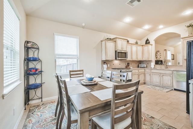 dining area with light tile patterned floors, sink, and vaulted ceiling