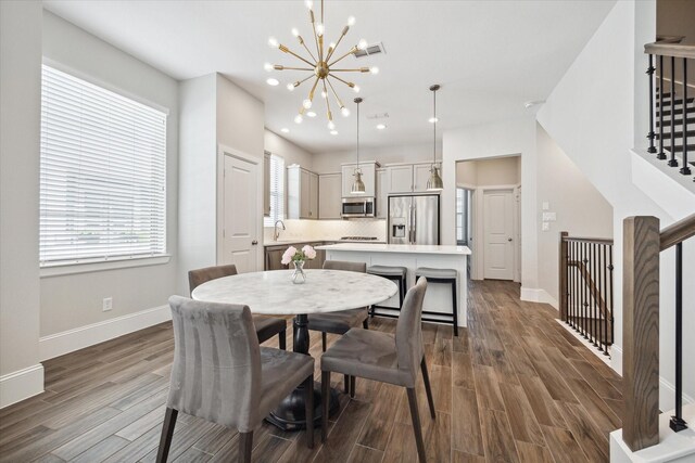 dining space featuring dark hardwood / wood-style floors, sink, and an inviting chandelier