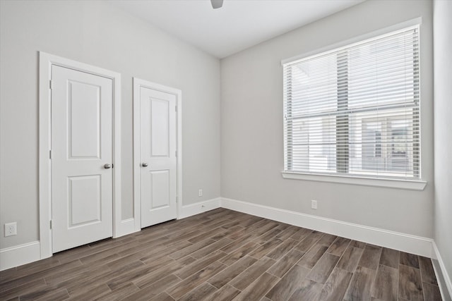 unfurnished bedroom featuring dark hardwood / wood-style flooring, multiple windows, and ceiling fan