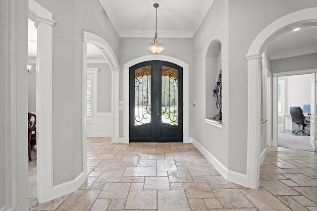 foyer entrance featuring ornate columns, crown molding, and french doors