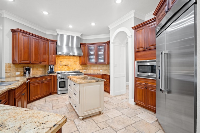 kitchen featuring tasteful backsplash, light stone counters, crown molding, wall chimney range hood, and high quality appliances