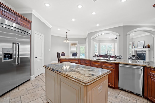 kitchen with stainless steel appliances, crown molding, sink, a center island, and hanging light fixtures