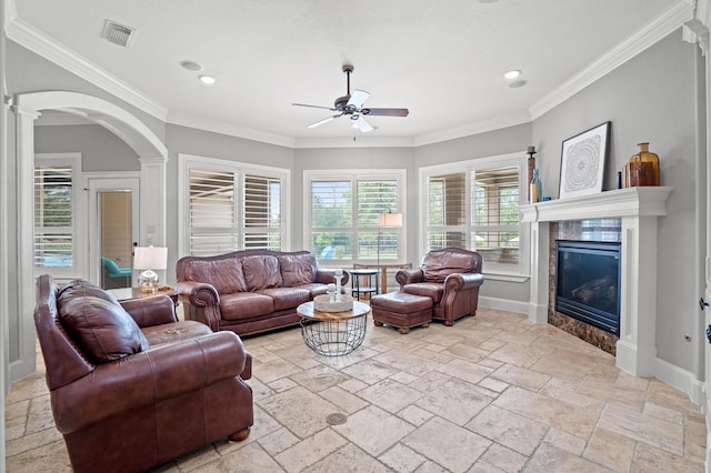 living room with ceiling fan, crown molding, and a fireplace