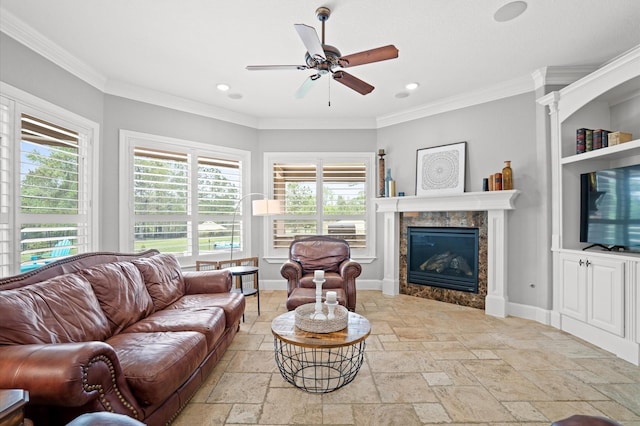 living room with a tile fireplace, ceiling fan, and ornamental molding