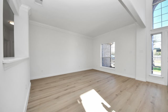 spare room with light wood-type flooring, crown molding, and a wealth of natural light