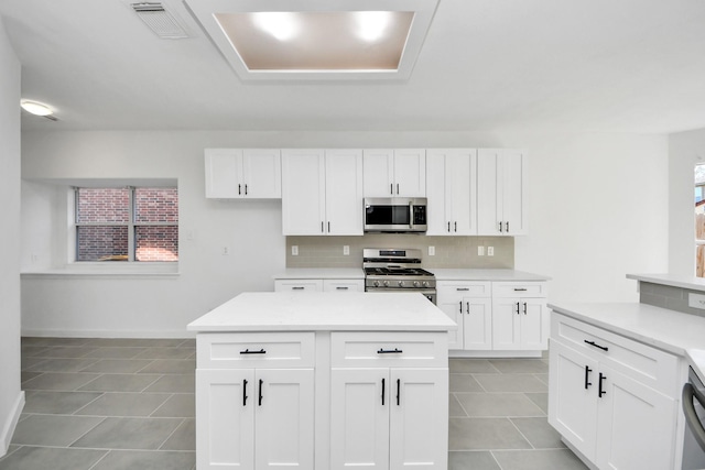 kitchen with white cabinets, appliances with stainless steel finishes, backsplash, and light tile patterned floors