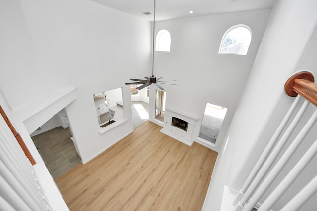 living room with ceiling fan, light hardwood / wood-style floors, and a towering ceiling