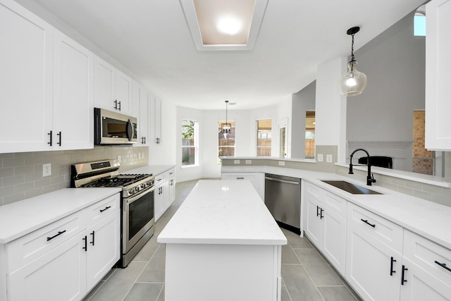 kitchen with sink, hanging light fixtures, tasteful backsplash, kitchen peninsula, and appliances with stainless steel finishes