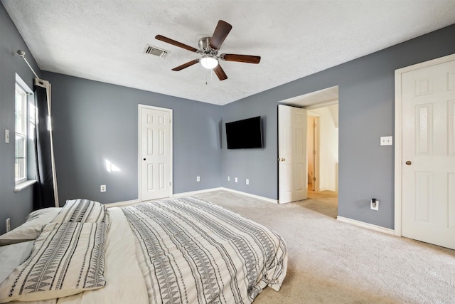 bedroom featuring a textured ceiling, ceiling fan, and light carpet