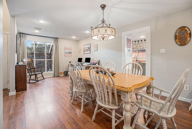 dining room featuring sink, dark hardwood / wood-style flooring, and a notable chandelier