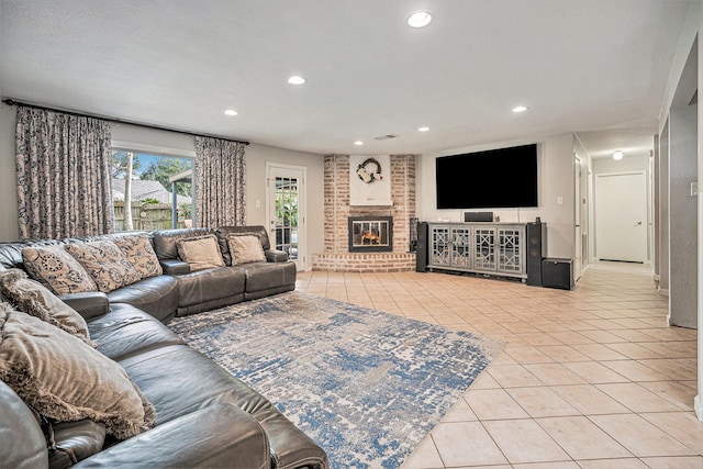 living room with a brick fireplace, a textured ceiling, and light tile patterned floors