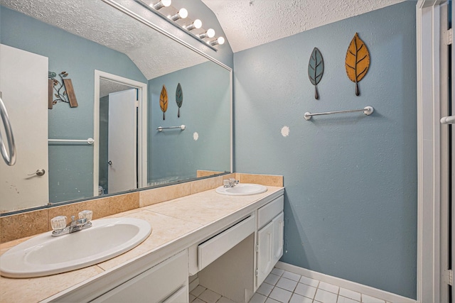 bathroom with a textured ceiling, vanity, lofted ceiling, and tile patterned floors