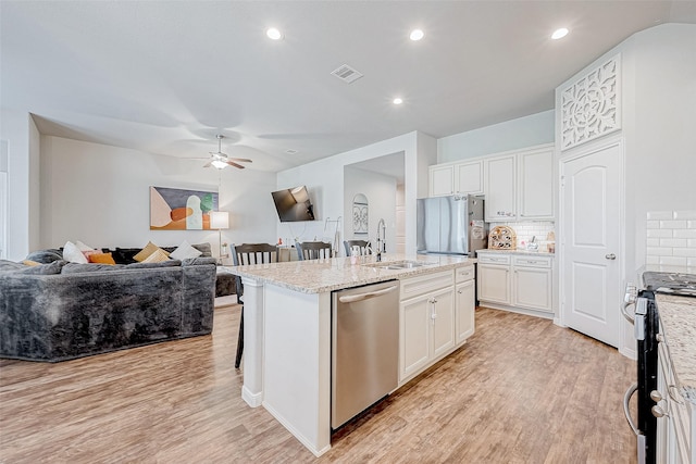 kitchen with white cabinetry, a kitchen island with sink, appliances with stainless steel finishes, and tasteful backsplash