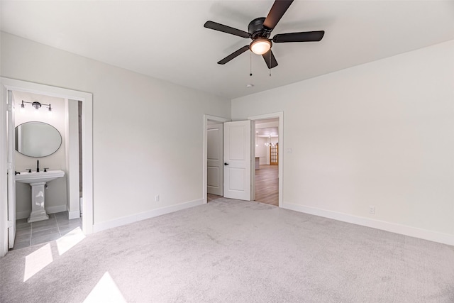 unfurnished bedroom featuring light carpet, connected bathroom, and ceiling fan