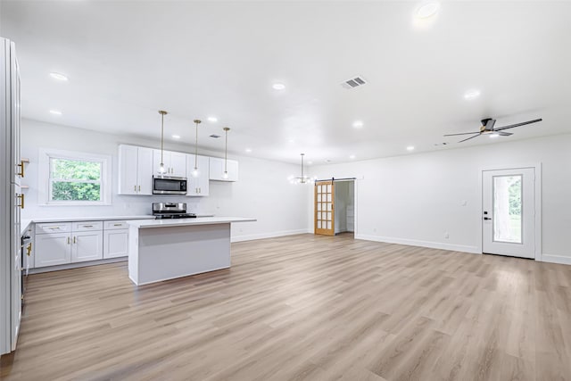 kitchen featuring hanging light fixtures, white cabinets, stainless steel appliances, and a kitchen island