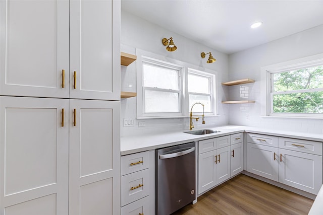 kitchen featuring dishwasher, sink, tasteful backsplash, hardwood / wood-style floors, and white cabinets