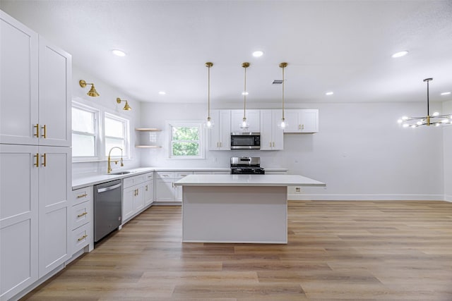 kitchen with white cabinets, stainless steel appliances, decorative light fixtures, and a kitchen island