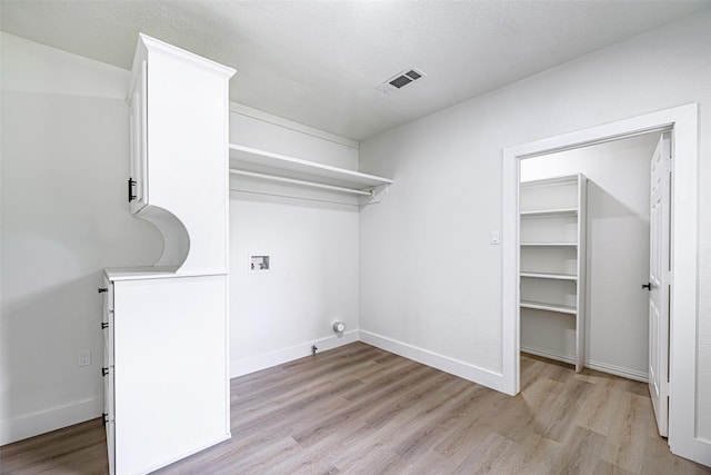 washroom with hookup for a washing machine, a textured ceiling, and light hardwood / wood-style flooring