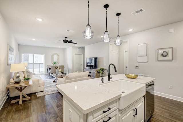 kitchen with light stone counters, stainless steel dishwasher, ceiling fan, sink, and an island with sink