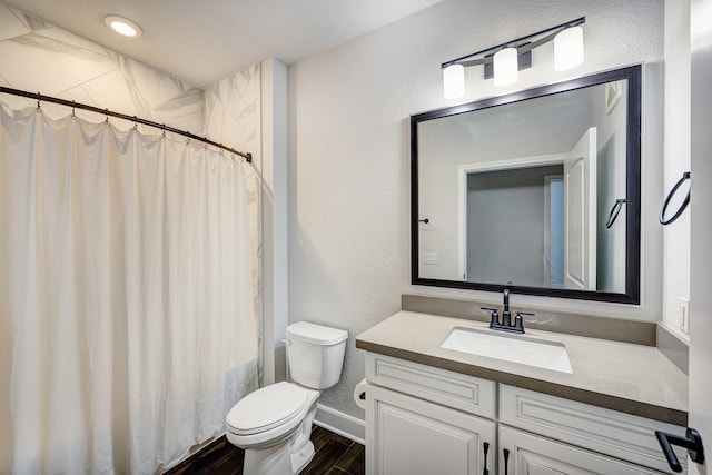 bathroom with toilet, vanity, and hardwood / wood-style flooring