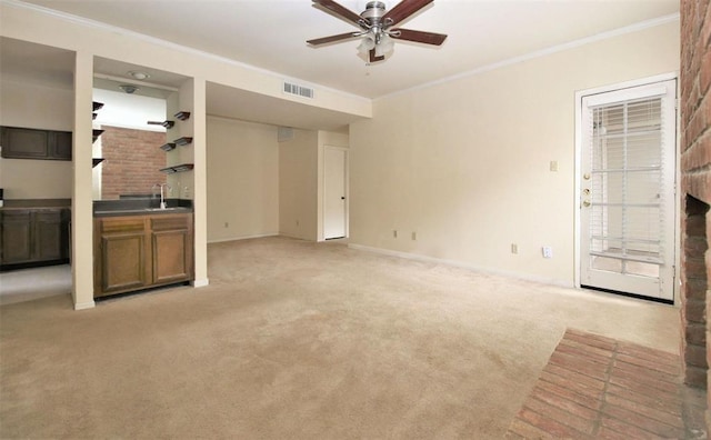 unfurnished living room featuring sink, ceiling fan, light colored carpet, and crown molding