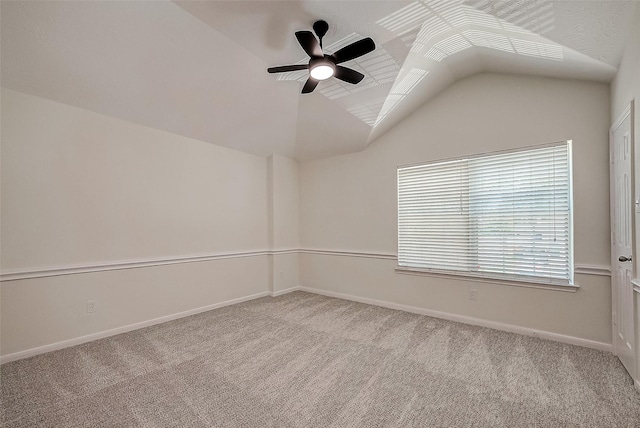 empty room with ceiling fan, light colored carpet, and vaulted ceiling