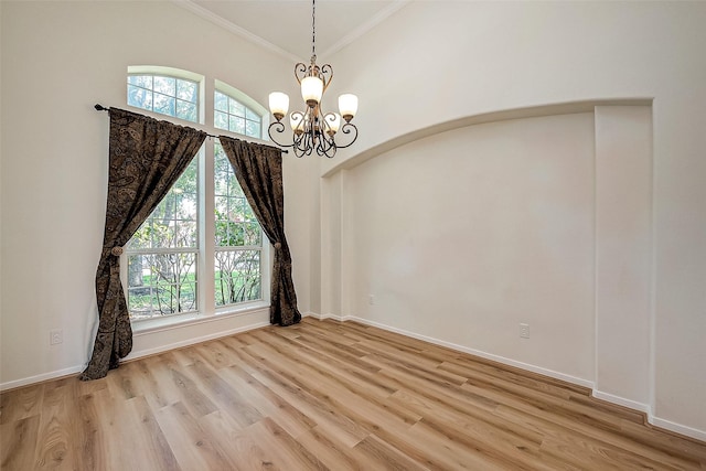 unfurnished room with a chandelier, light hardwood / wood-style floors, a wealth of natural light, and crown molding