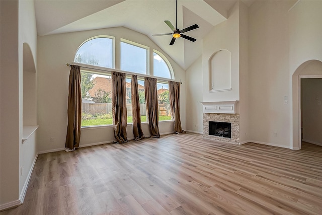 unfurnished living room featuring a fireplace, light hardwood / wood-style floors, high vaulted ceiling, and ceiling fan