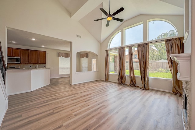 unfurnished living room featuring light hardwood / wood-style floors, high vaulted ceiling, and ceiling fan