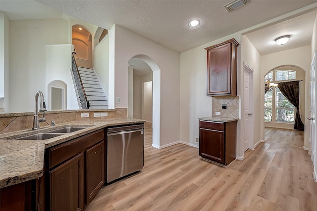 kitchen with a textured ceiling, dishwasher, sink, and light hardwood / wood-style flooring