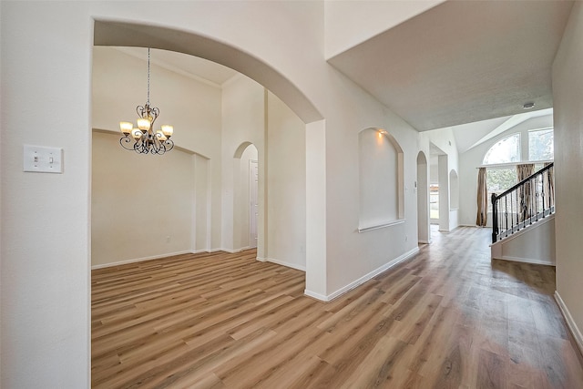 corridor with lofted ceiling, light hardwood / wood-style flooring, and a chandelier