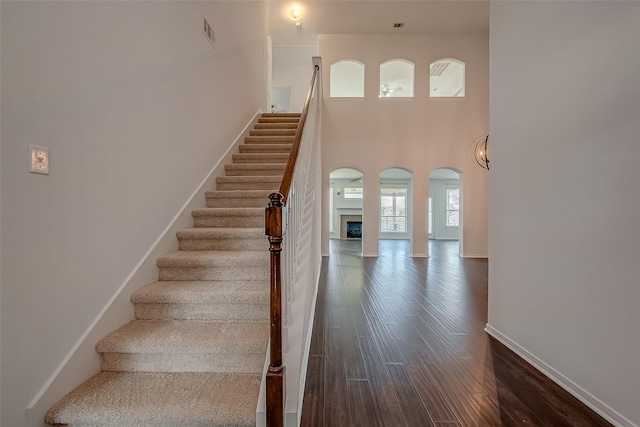 stairway with hardwood / wood-style flooring and a high ceiling