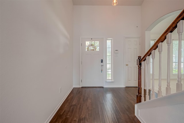 foyer entrance with a towering ceiling and dark hardwood / wood-style floors