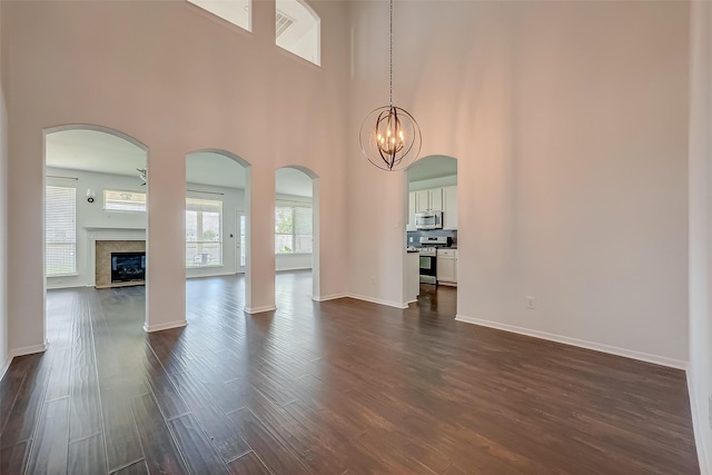 interior space featuring an inviting chandelier, a fireplace, dark hardwood / wood-style floors, and a towering ceiling