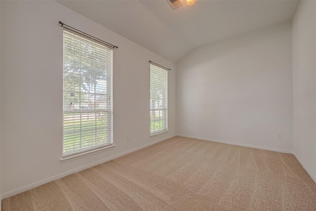 carpeted empty room with plenty of natural light and lofted ceiling