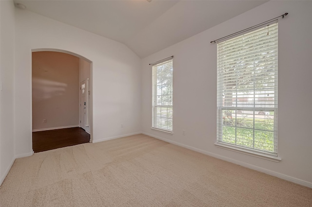 carpeted empty room featuring lofted ceiling