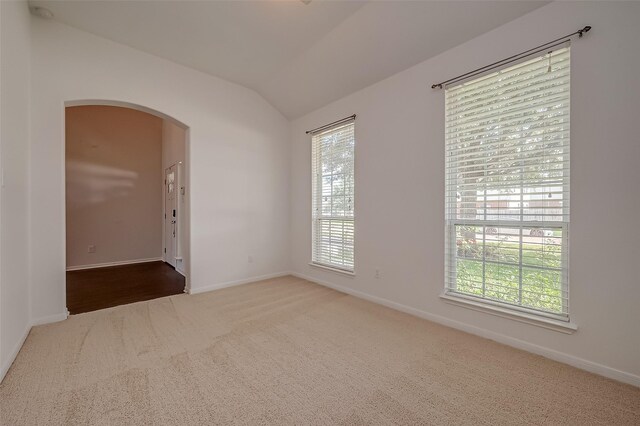 carpeted spare room featuring lofted ceiling